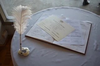 Marriage register and certificate on a table beside a feather pen