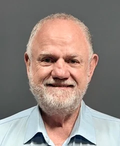 Kelvin Brown, smiling, with a white beard and a pale blue shirt