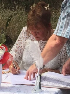 A bride signing the marriage register, a white feather pen beside her