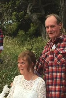 A bride laughing beside her groom in a red flannel shirt